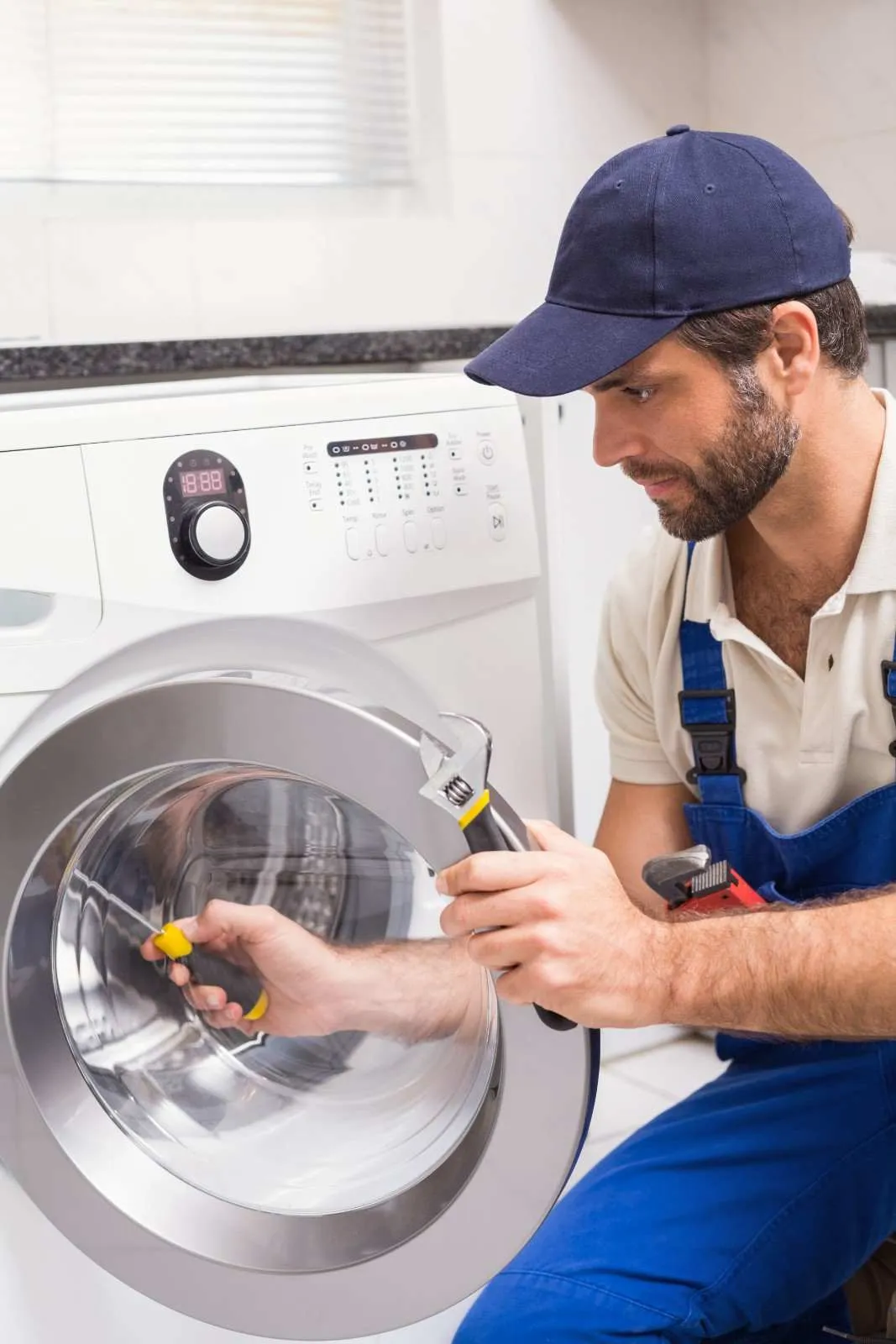 Technician repairing a front load washing machine in a home