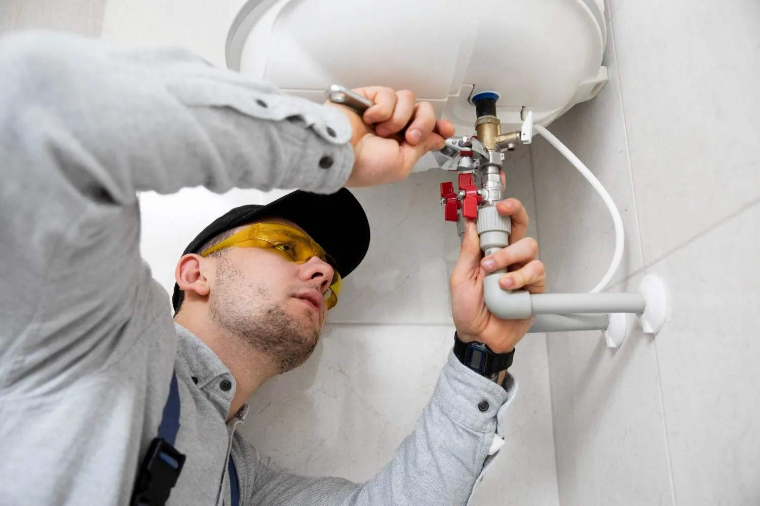 Technician fitting a valve on a wall mounted water heater